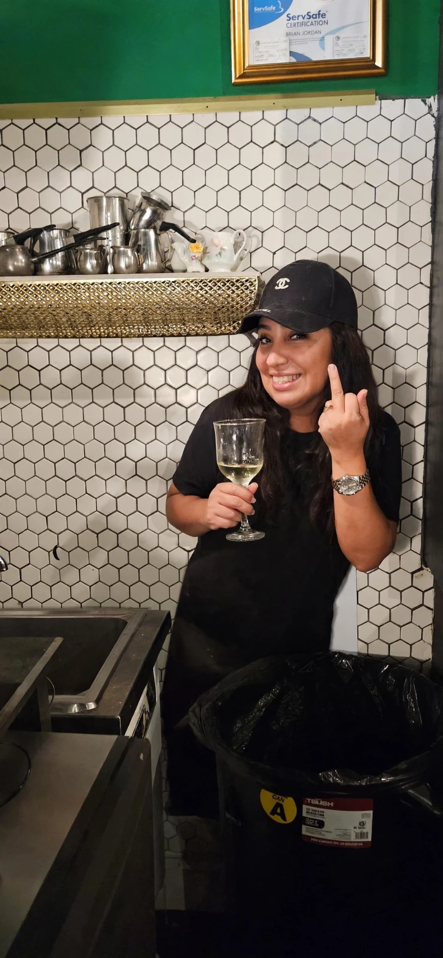 Gloria smiling in the Jordan's Wine Bar kitchen, holding a glass of white wine