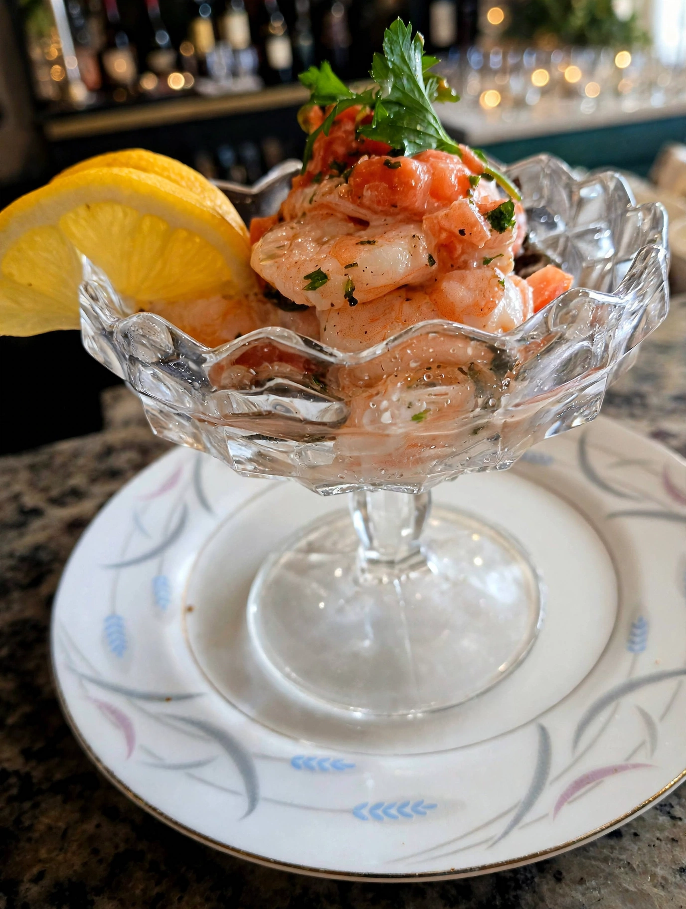Shrimp cocktail in a faceted glass dish at Jordan's Wine Bar, garnished with parsley and a lemon slice
