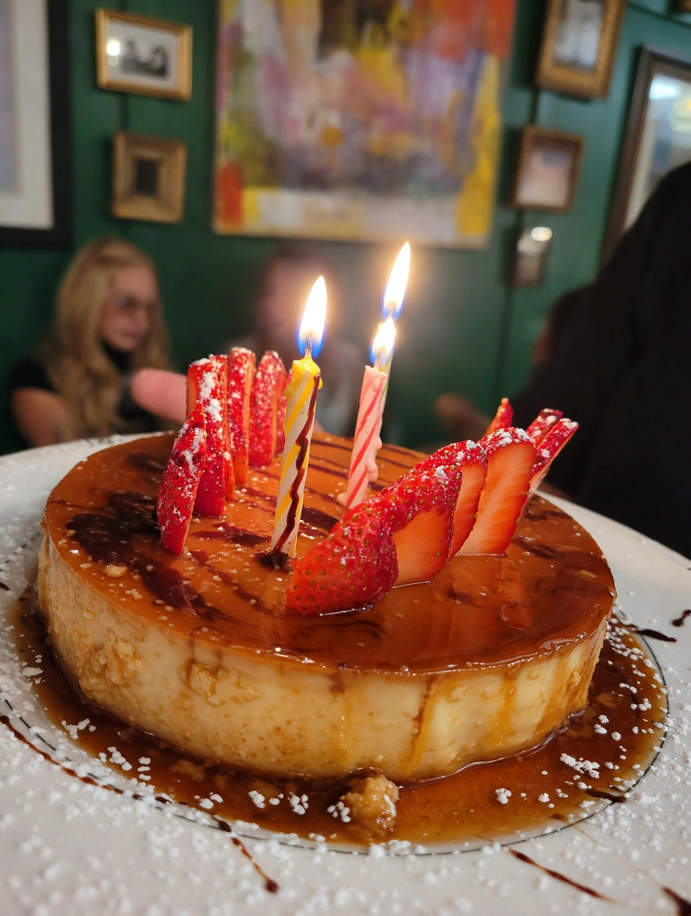 Caramel flan with strawberries and candles in the dining room