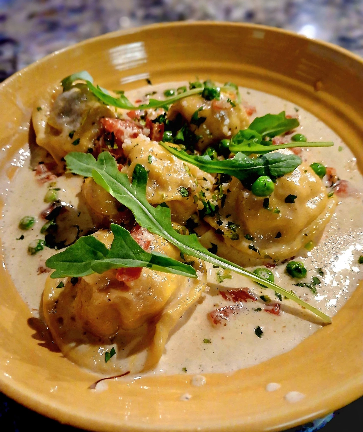 Ravioli with peas, prosciutto and arugula in cream sauce