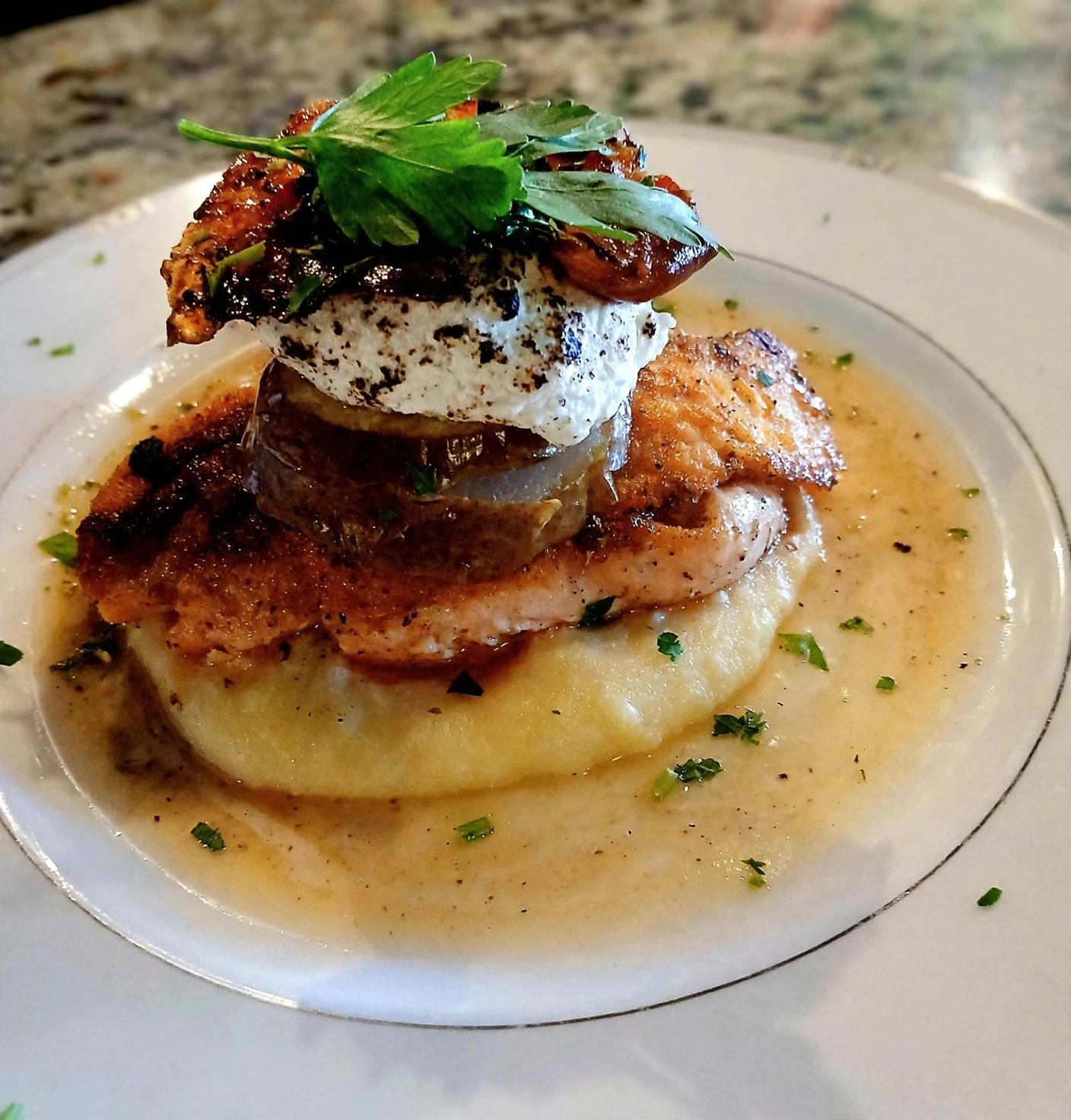 Seared salmon stacked over polenta with burrata and herbs